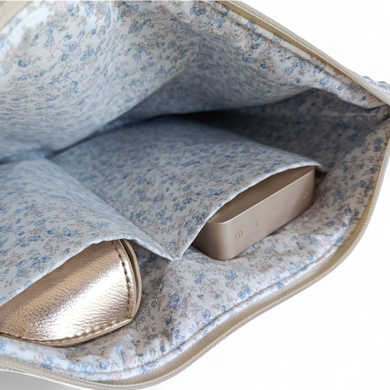 internal-view-of-a-laptop-sleeve-showing-blue-floral-lining-and-two-padded-pockets-holding-accessories