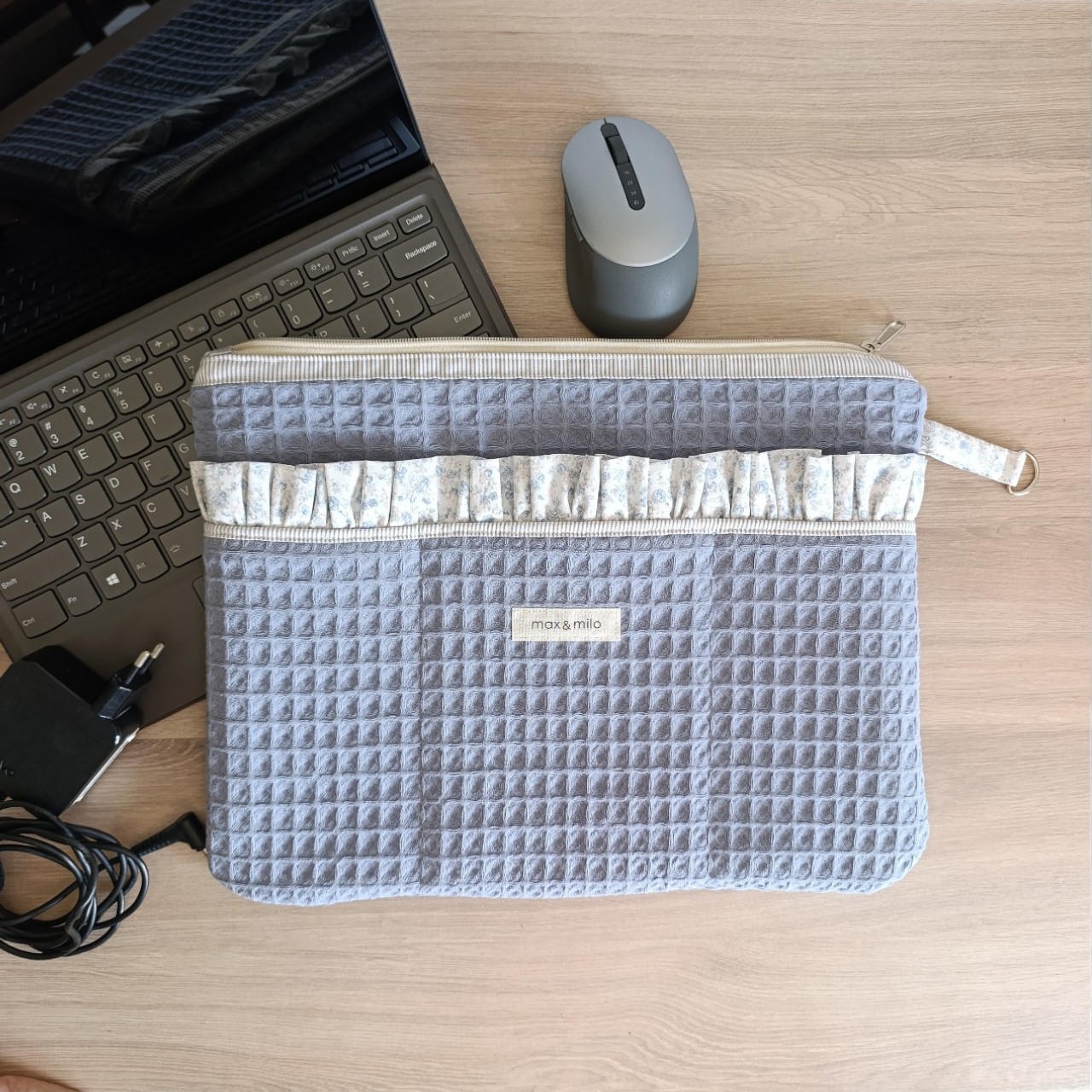 front-view-of-a-blue-waffle-weave-laptop-sleeve-with-a-decorative-ruffled-edged-front-pocket-with-the-brand-name-max-&-milo-stitched-onto-the-front-of-the-sleeve