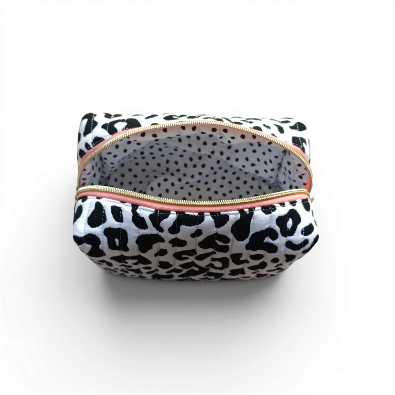 lining-view-of-a-black-and-white-quilted-boxy-bag-with-a-salmon-coloured-zipper-and-brand-lable