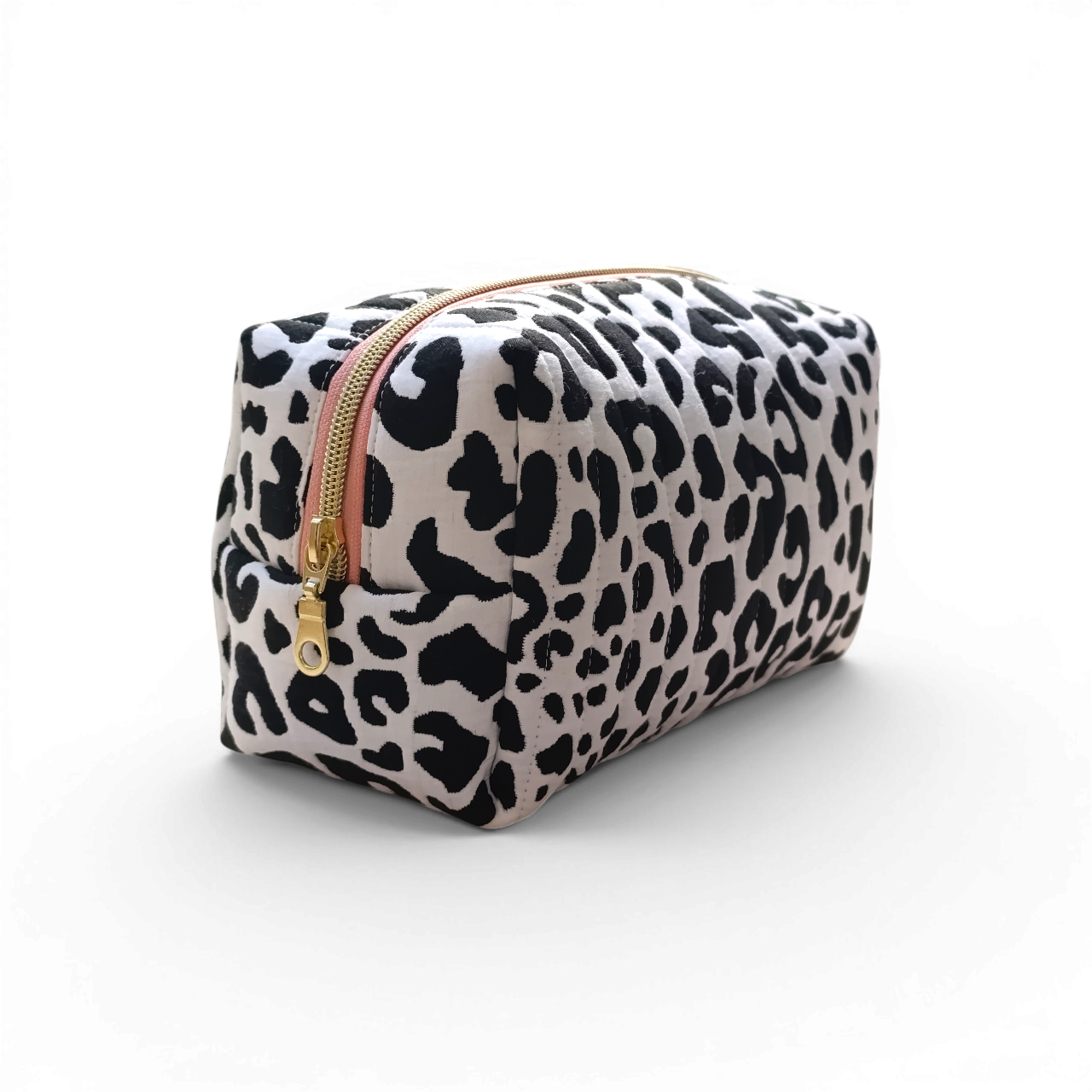 oblique-view-of-a-black-and-white-quilted-boxy-bag-with-a-salmon-coloured-zipper-and-brand-lable