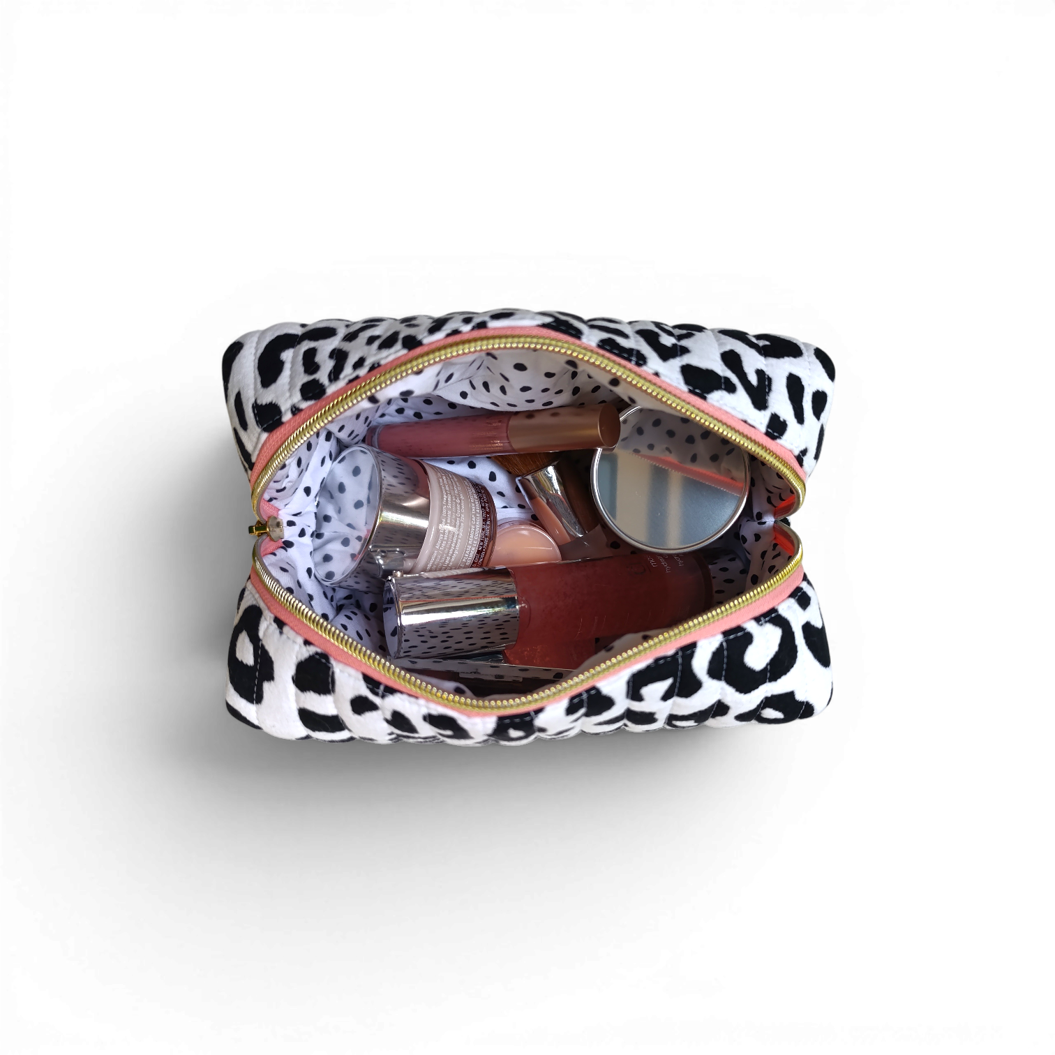 top-down-styled-view-of-a-black-and-white-quilted-boxy-bag-with-a-salmon-coloured-zipper-and-brand-lable