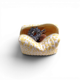 styled-view-of-an open-yellow-and-white-quilted-boxy-bag-with-a-white-and-gold-coloured-zipper-and-yellow-delulu-brand-lable-styled-with-facial-products